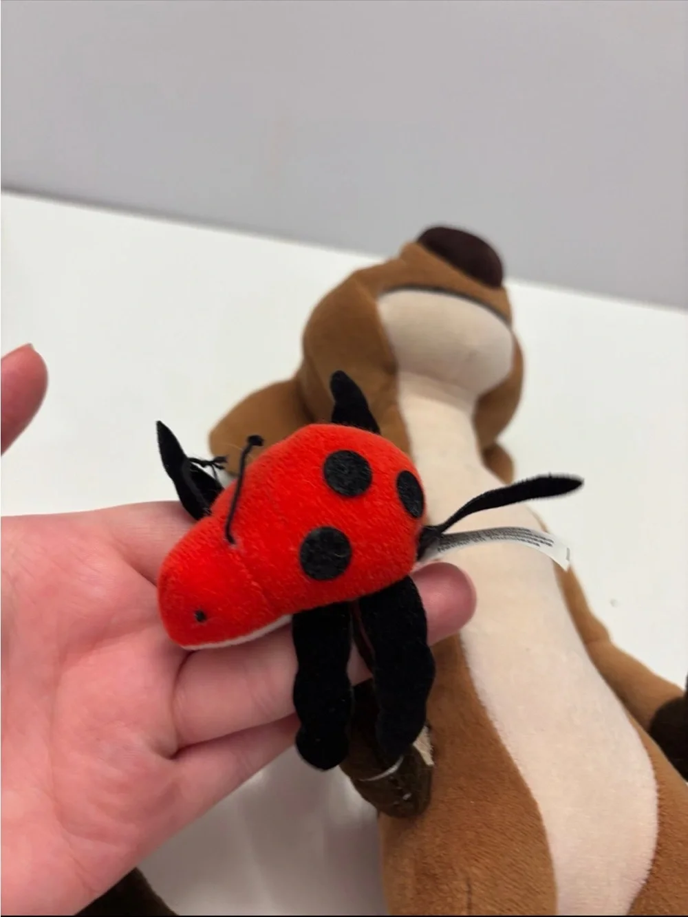 Disney The Lion King Timon plush toy holding a small red ladybug